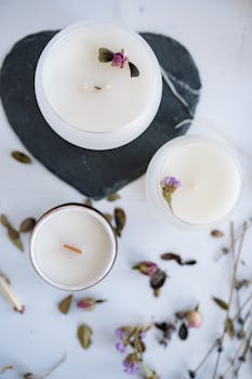 Top view of elegant floral scented candles on slate with dried flowers, perfect for aromatherapy.