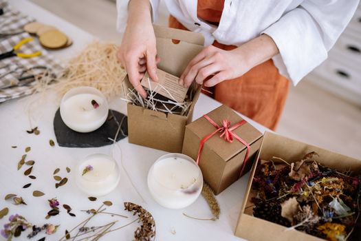 Person assembling eco-friendly candle gift boxes with natural materials.