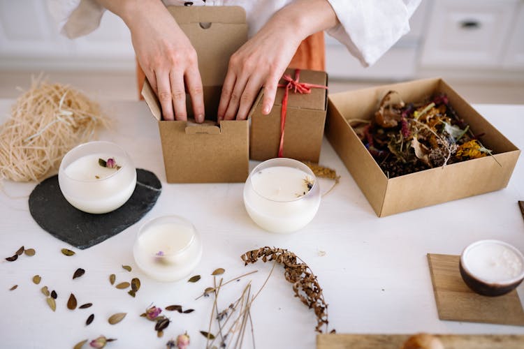 A Person Packing Candles On Cardboard Boxes