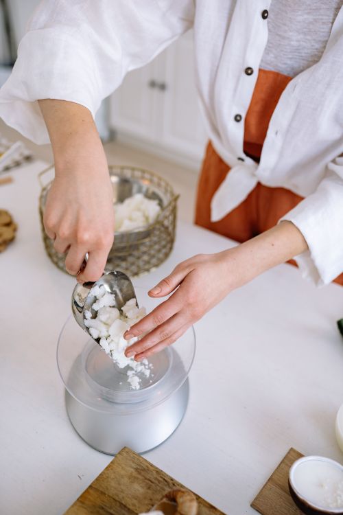 Free A woman measuring wax with a scale for crafting handmade candles, showcasing precision and creativity. Stock Photo