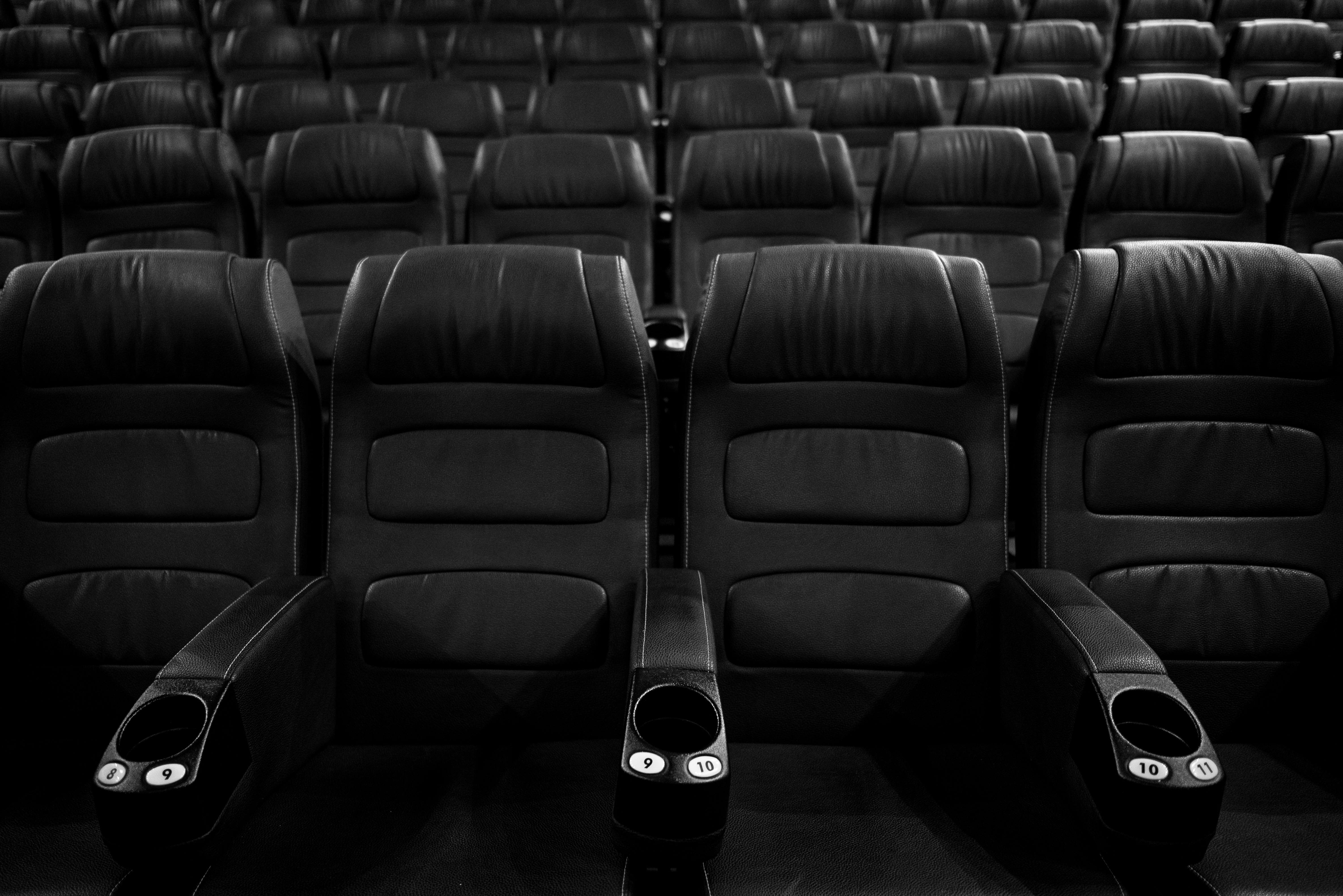 Free Grayscale image of empty leather cinema seats in a neat row. Stock Photo