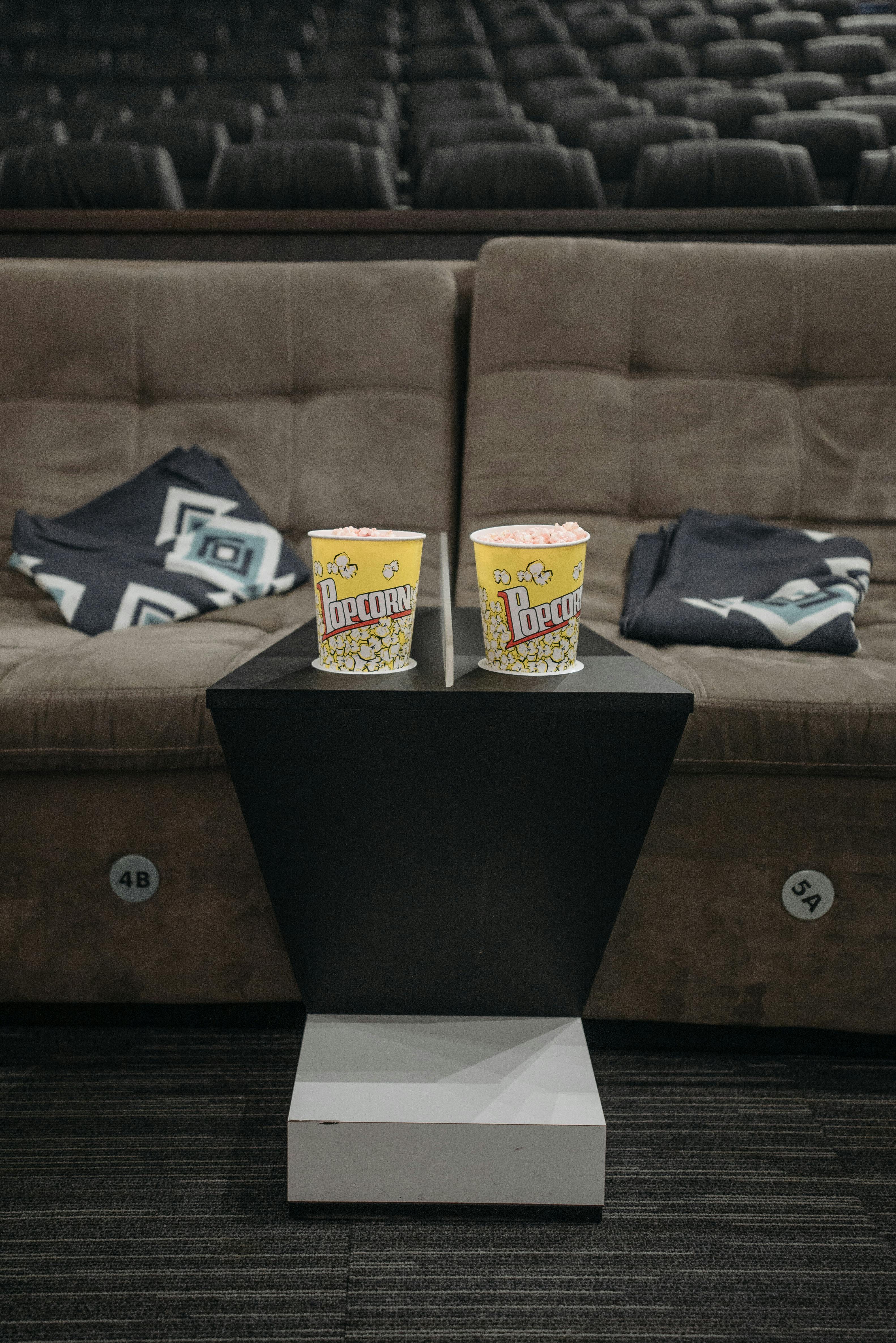Free Luxurious cinema seating with popcorn, perfect for movie night in a cozy theater setting. Stock Photo