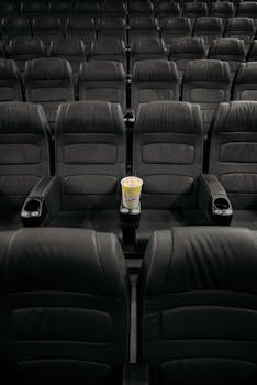 An empty cinema with rows of black seats and popcorn in focus, hinting at movie anticipation.