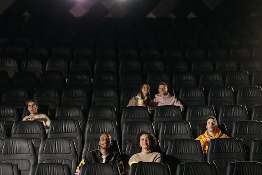 A small diverse group of people watching a movie in an almost empty theater.