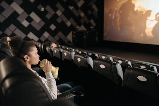 A young woman drinking and watching a movie alone in a cozy cinema auditorium.