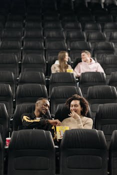 Two couples enjoying popcorn while watching a movie in an empty cinema.