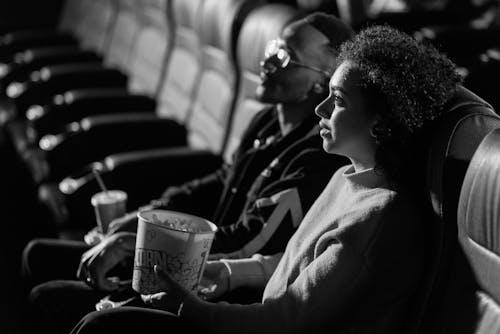 Grayscale Photo of a Man and a Woman Watching a Movie Together