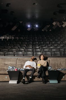 A couple enjoys a quiet moment in an empty movie theater, holding popcorn.