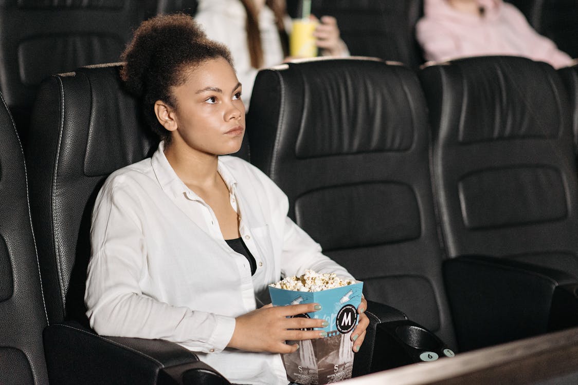 Free Woman Holding Popcorn Watching a Movie Stock Photo