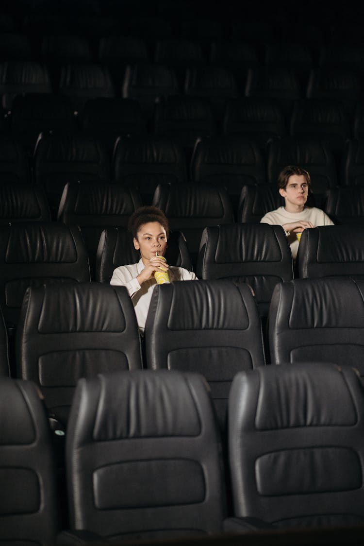 A Woman Sitting On Black Leather Seat Sipping A Drink