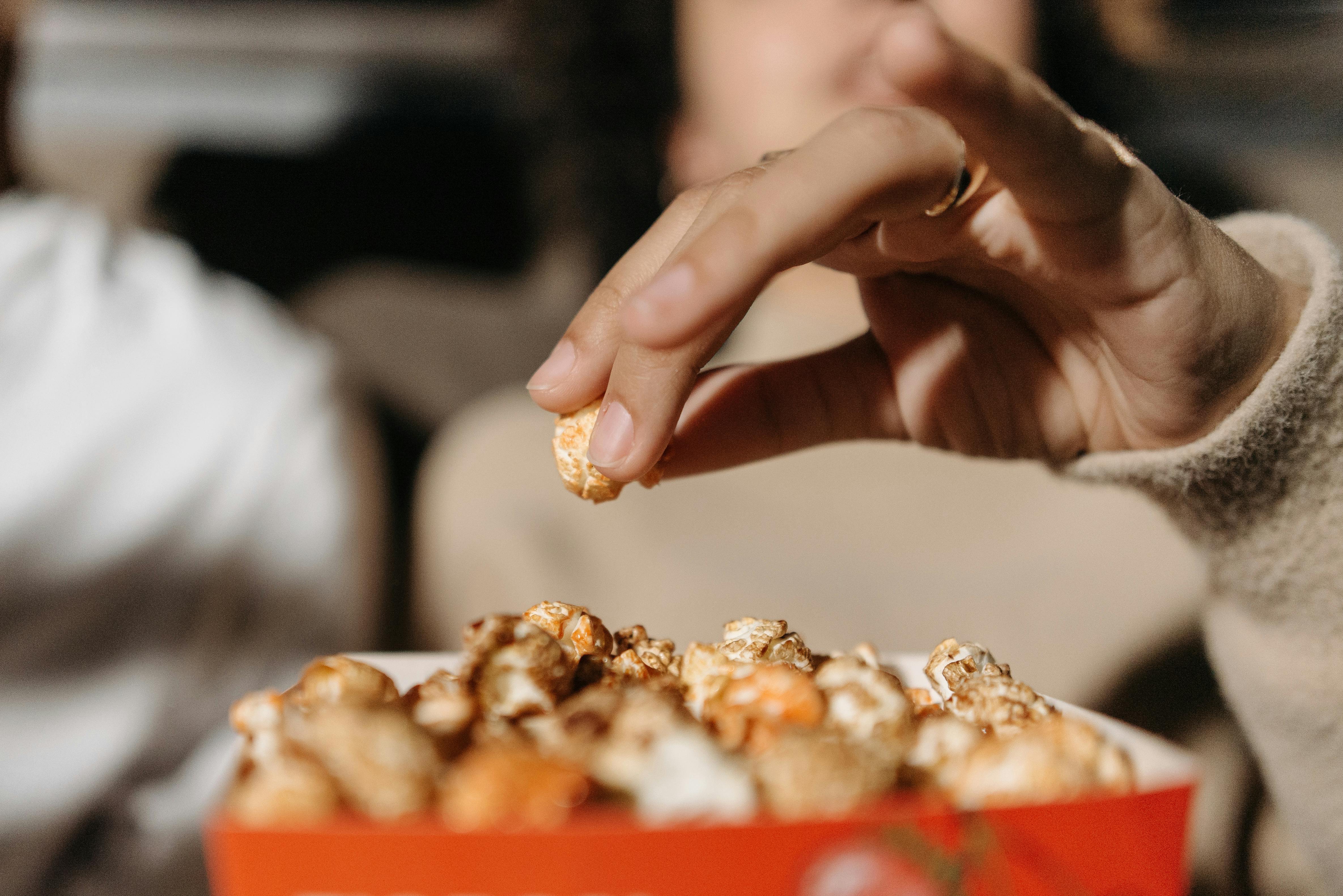 a person eating popcorn while watching a movie