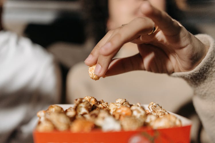 A Person Eating Popcorn While Watching A Movie