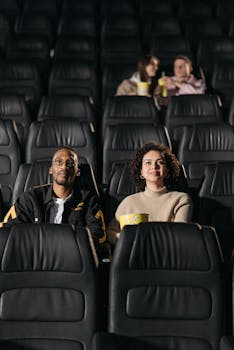 Two couples enjoying a movie in a theater setting. Popcorn and cozy atmosphere add to the casual vibe.