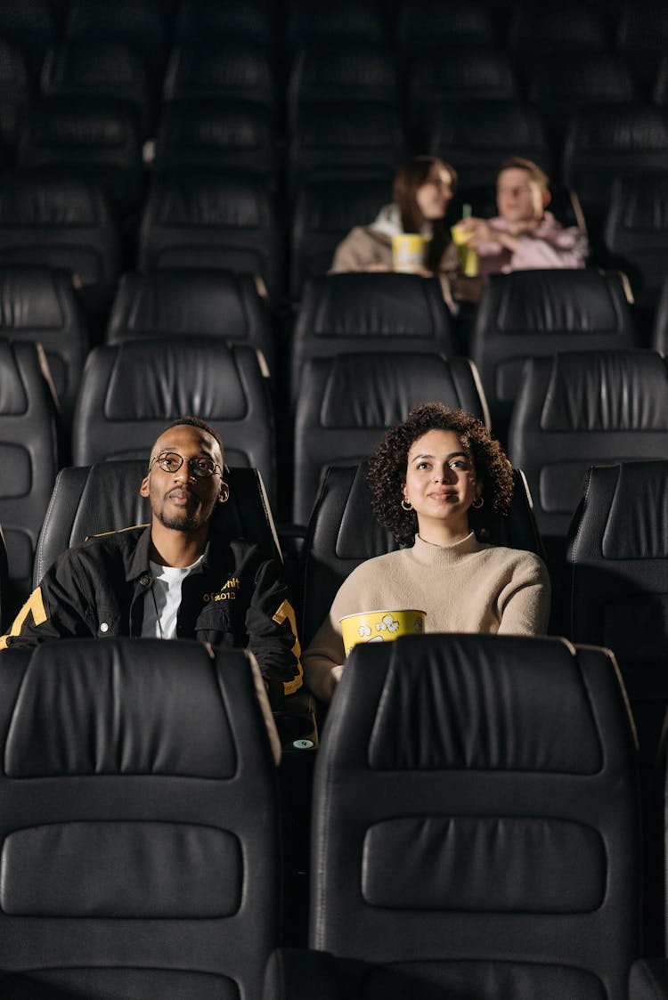 A Couple Sitting On Leather Seats On A Movie Theater