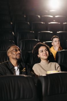 A cheerful couple enjoying a movie together in a theater with a blurred background.
