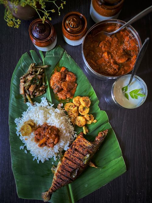 Free Delicious South Indian meal served on banana leaf with rice and fish curry. Stock Photo