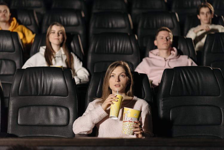 Woman Watching Movie In A Cinema With Popcorn And Cold Drink