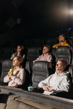 People enjoying a movie in a theater with snacks and drinks, focus on audience engagement.