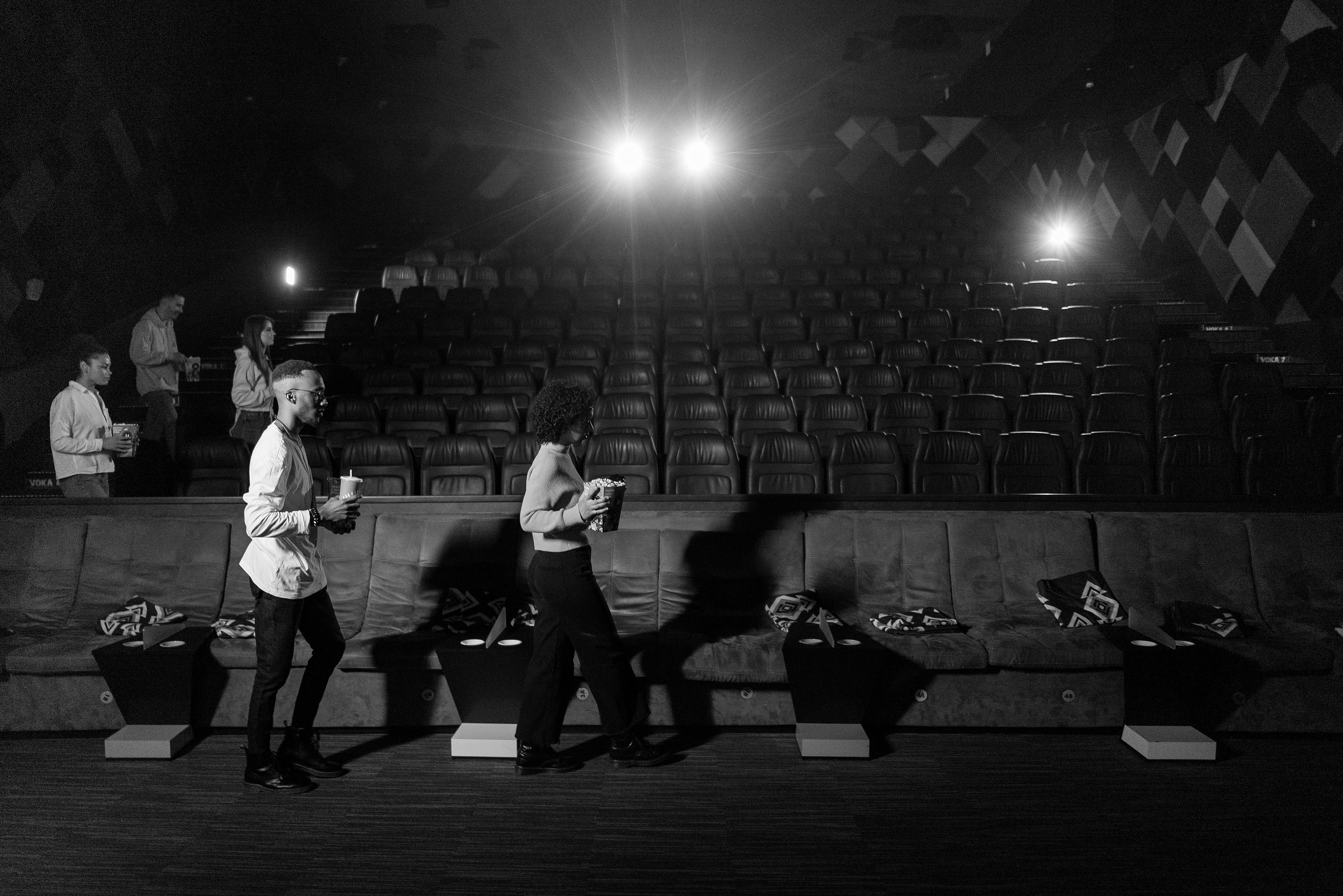 Free Monochrome view of people walking in an empty cinema with bright lights. Stock Photo