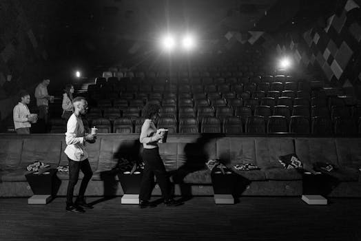 Monochrome view of people walking in an empty cinema with bright lights.
