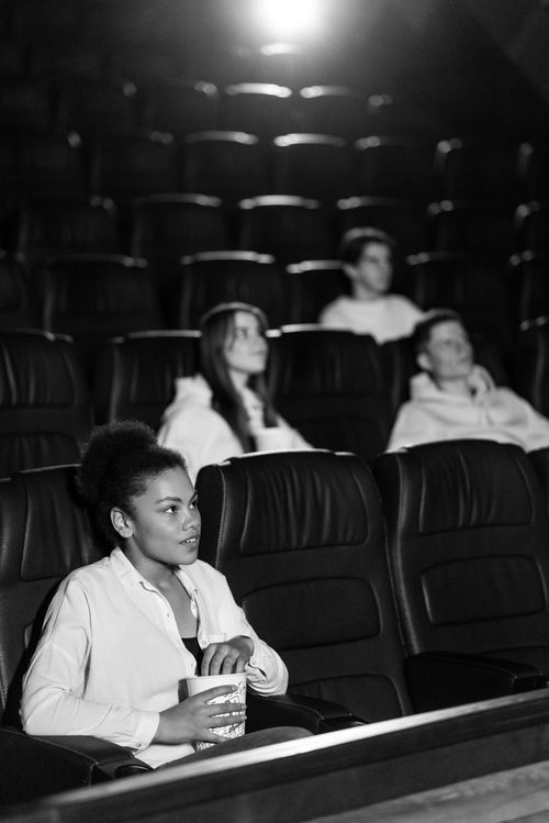 Free Audience watching a movie in a black and white cinema setting, holding popcorn. Stock Photo