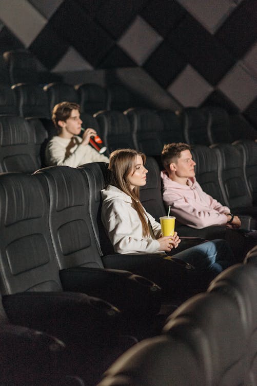 Three People Watching a Movie in a Movie Theater