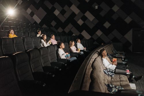 Free Audience enjoying a film screening in a modern theater with popcorn and drinks. Stock Photo