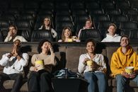 People with Mixed Reactions Sitting with Buckets of Popcorns