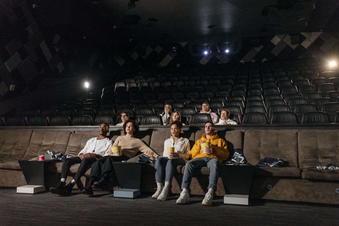 Free A diverse group of people enjoying a movie screening in an empty cinema with popcorn. Stock Photo