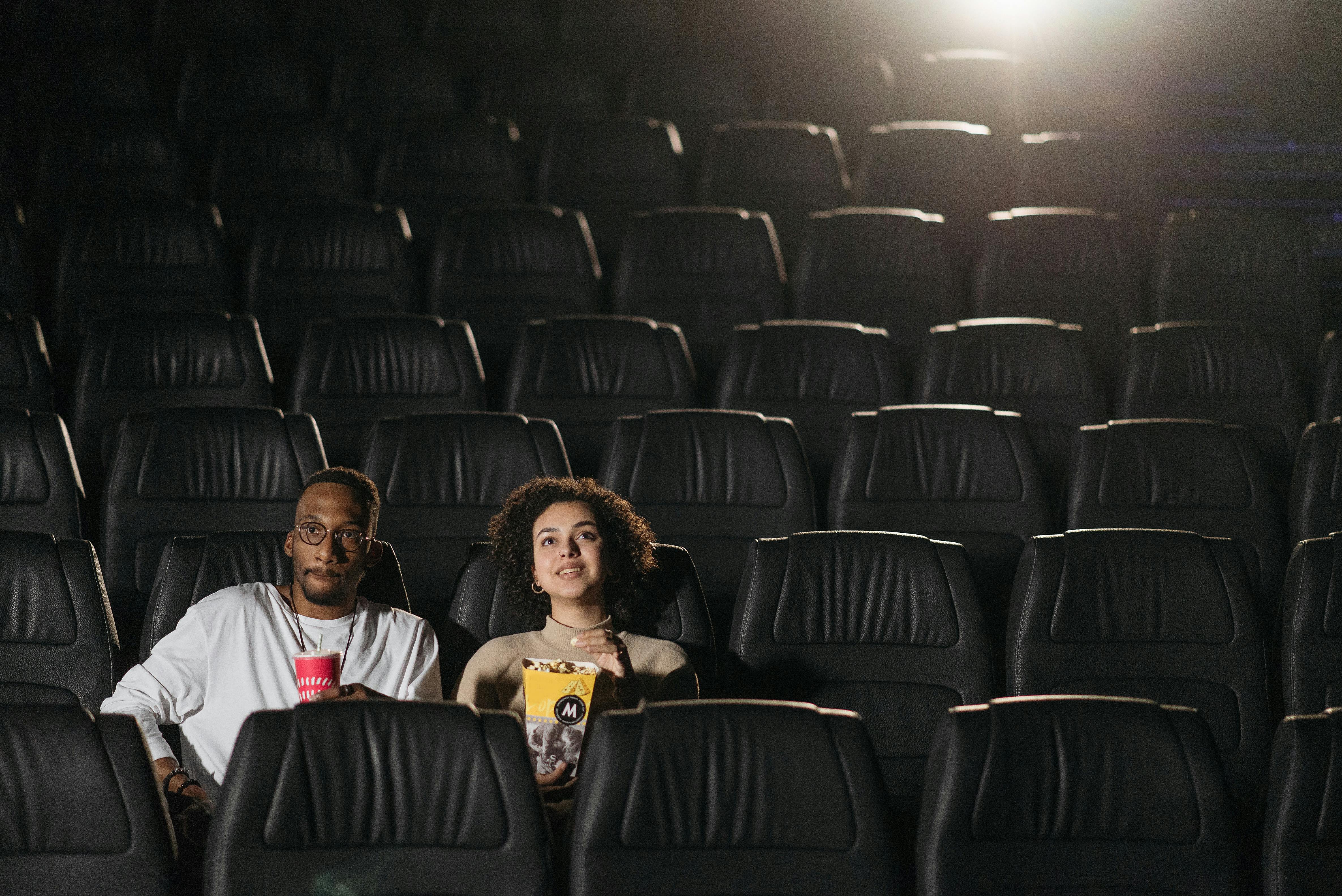 Free A couple enjoying drinks and snacks during a movie night in an empty cinema. Stock Photo