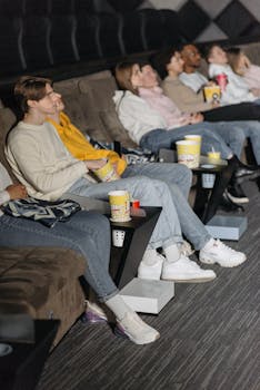 Group of people enjoying a movie in theater with popcorn and drinks