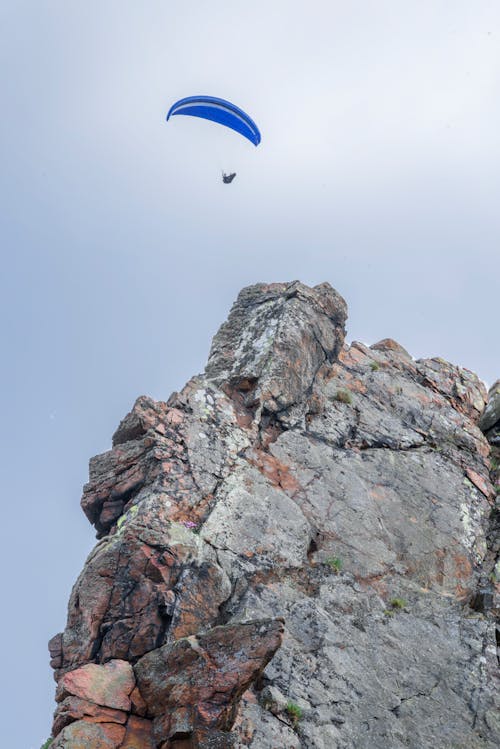 Free Person Parachuting Over a Rocky Cliff Stock Photo