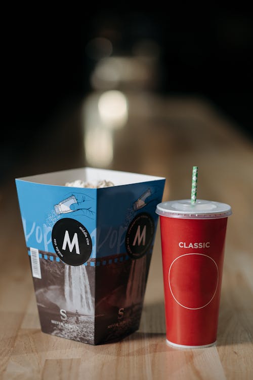 A Paper Tumbler Beside a Red Disposable Cup with Straw