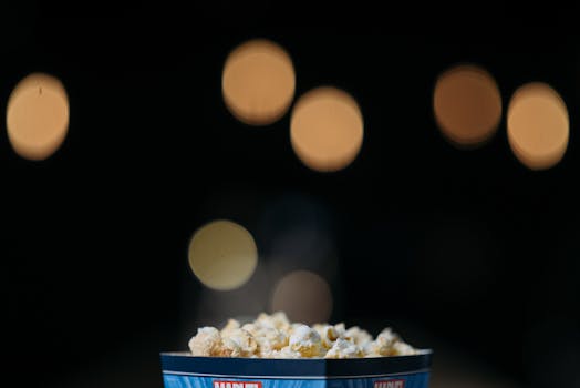 A close-up view of popcorn in a themed bucket with movie bokeh background.