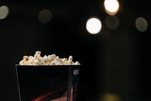 Close-up of fresh popcorn in a cinema-style box against a bokeh background, perfect for movie night themes.