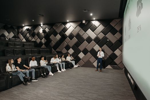 A group attentively listens to a business presentation in a modern, stylish auditorium.