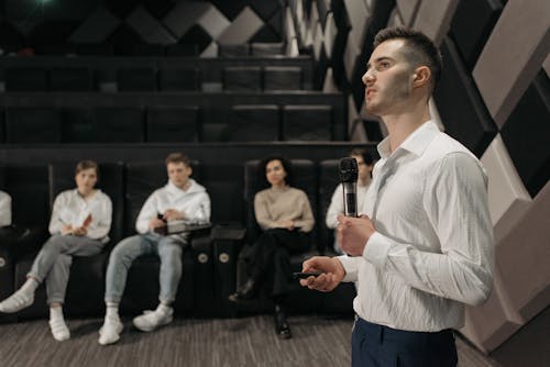 Man in White Dress Shirt Holding Microphone Doing a Presentation