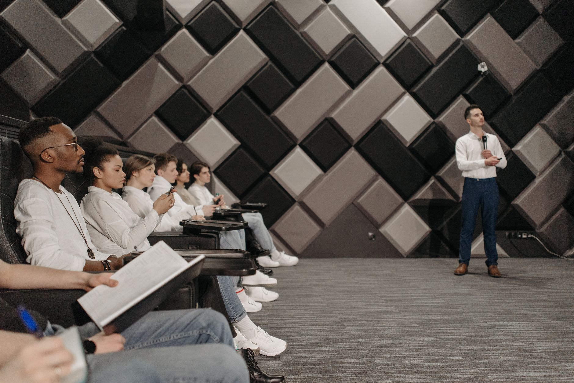 Diverse group of professionals attending a seminar indoors, listening intently to a presenter.
