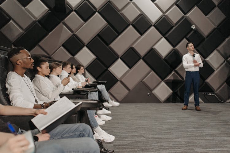 Group Of People Watching A Speaker Doing A Presentation