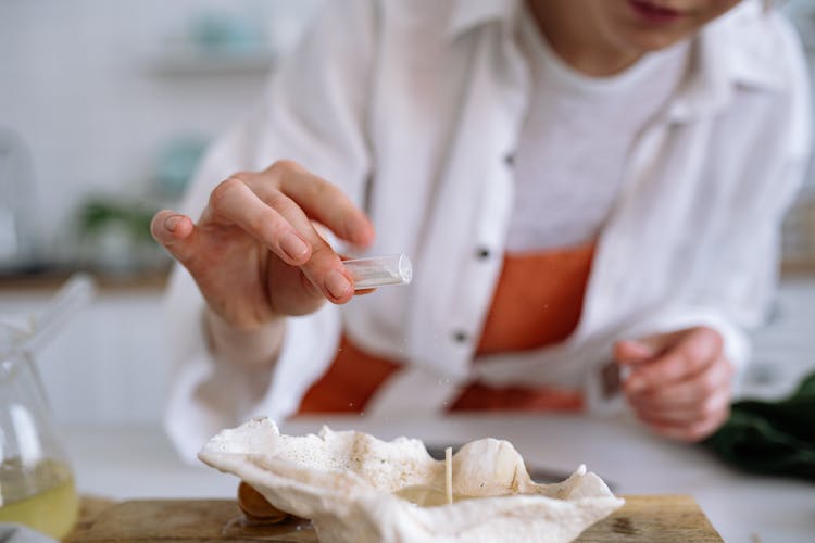 Person In White Long Sleeve Shirt Making A Candle