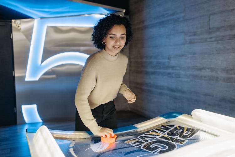 A Pretty Woman Playing Air Hockey In An Arcade