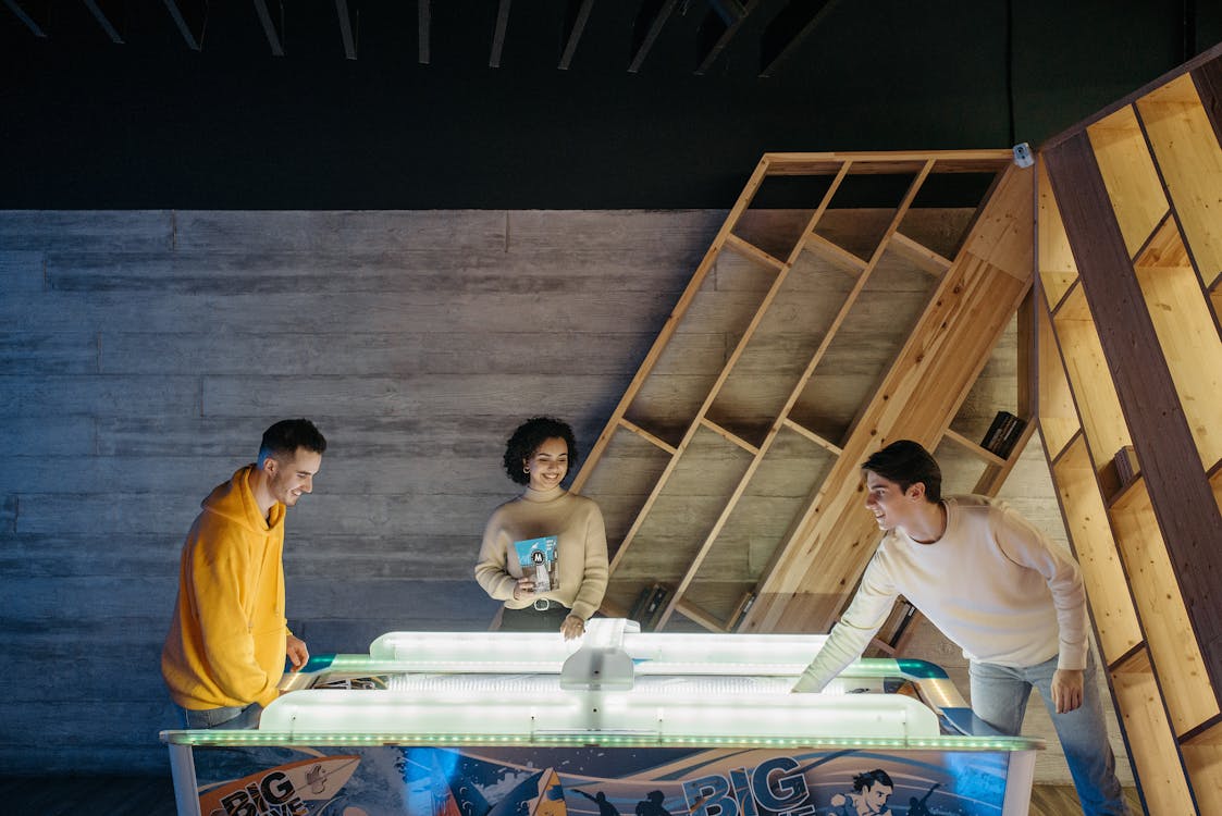 Free A Woman Watching Men Playing Air Hockey Stock Photo