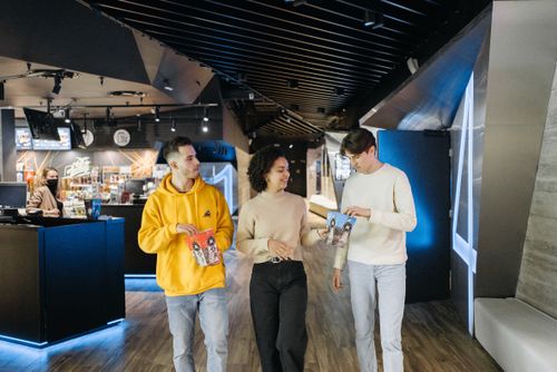 Free Three friends walking in a movie theater with popcorn, ready for a cinematic experience. Stock Photo