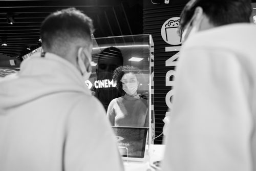 Free Black and white image of cinema ticket counter with masked individuals during pandemic. Stock Photo
