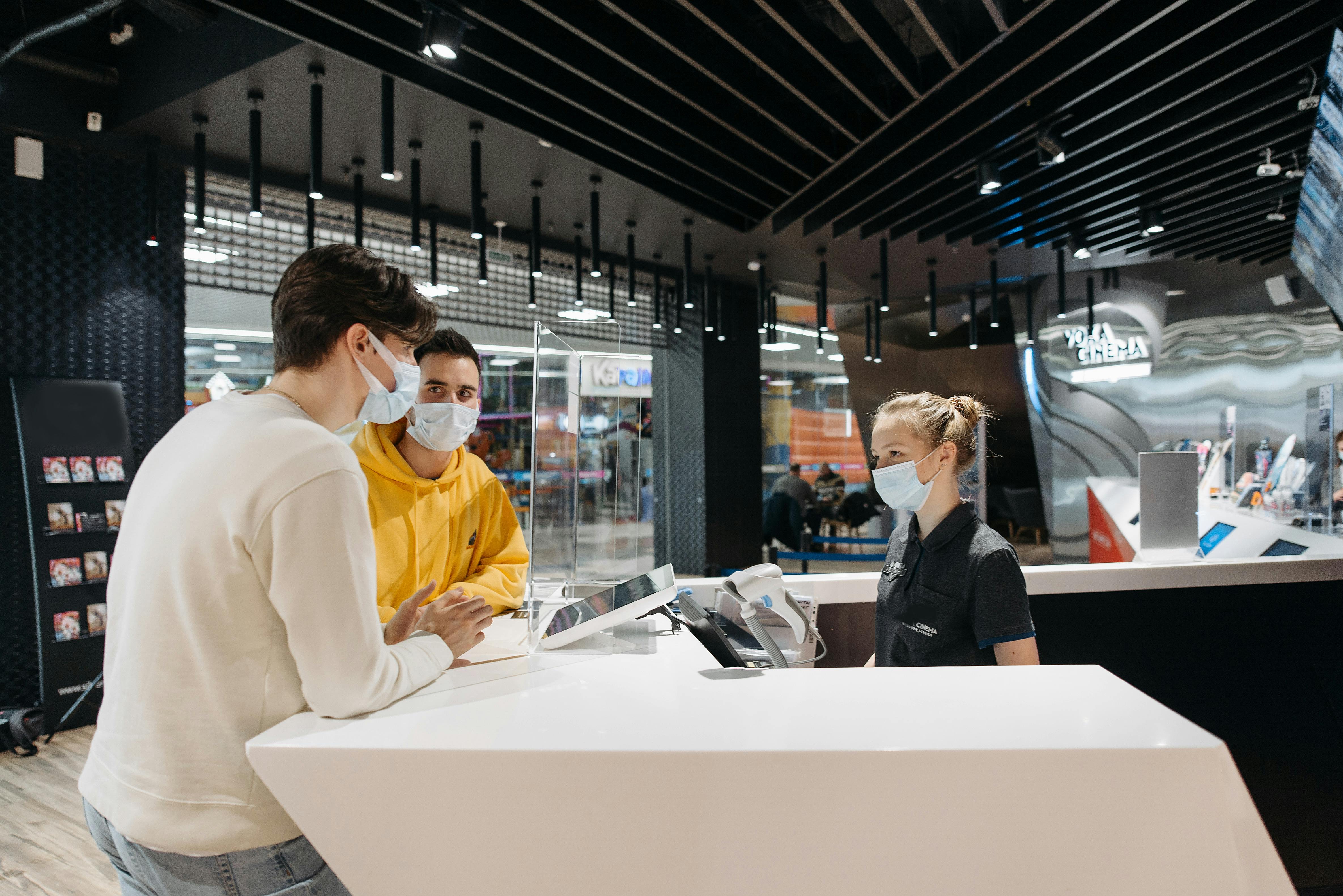 two guys standing at a counter with a female cashier 
