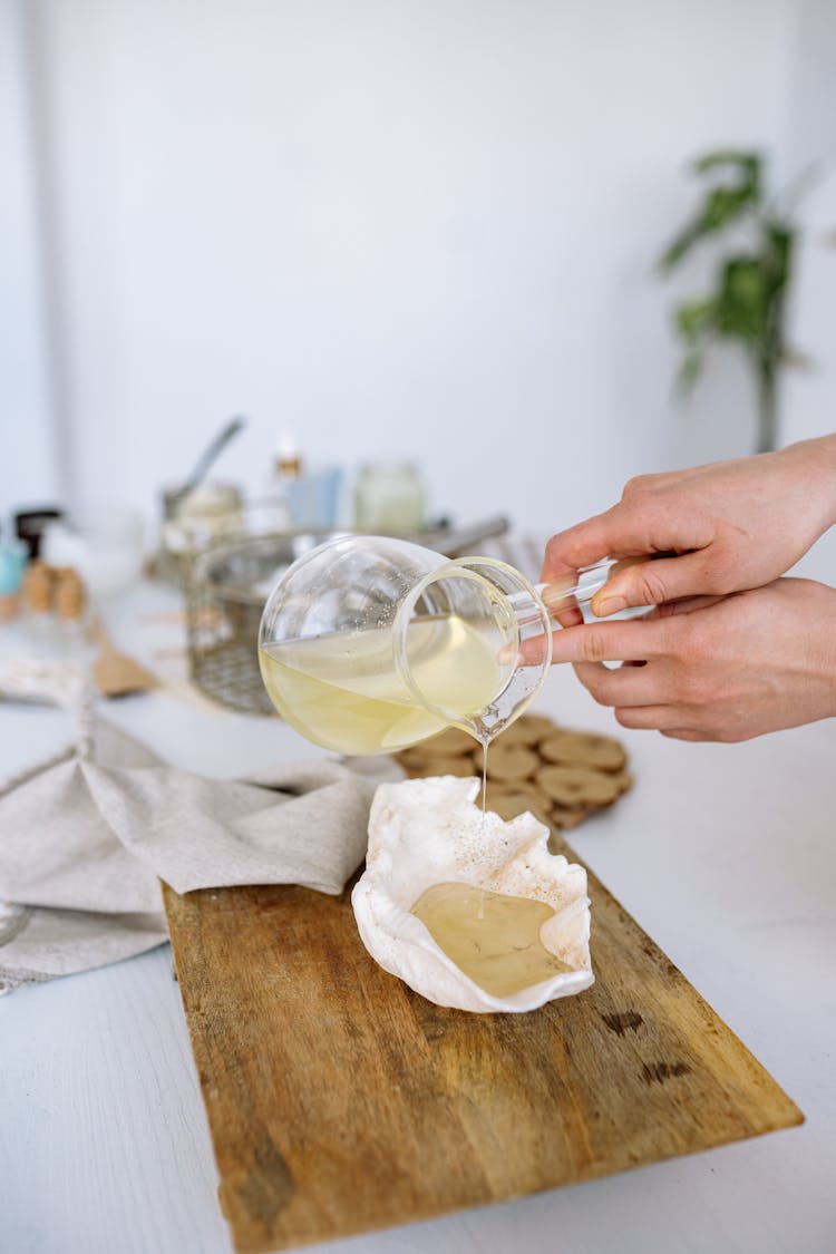 A Person Pouring A Clear Liquid On A White Seashell