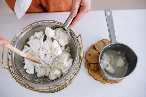Free Hands crafting candles with melted wax in an indoor workshop setting. Stock Photo