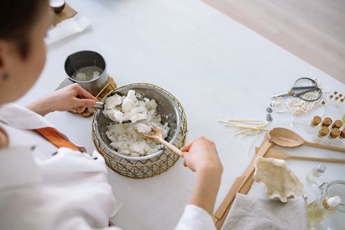 Free Person melting wax for candle making with tools on a white workspace. Stock Photo
