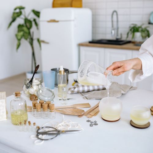 Free Person pouring gel wax to make candles in a home kitchen setup with tools and materials. Stock Photo