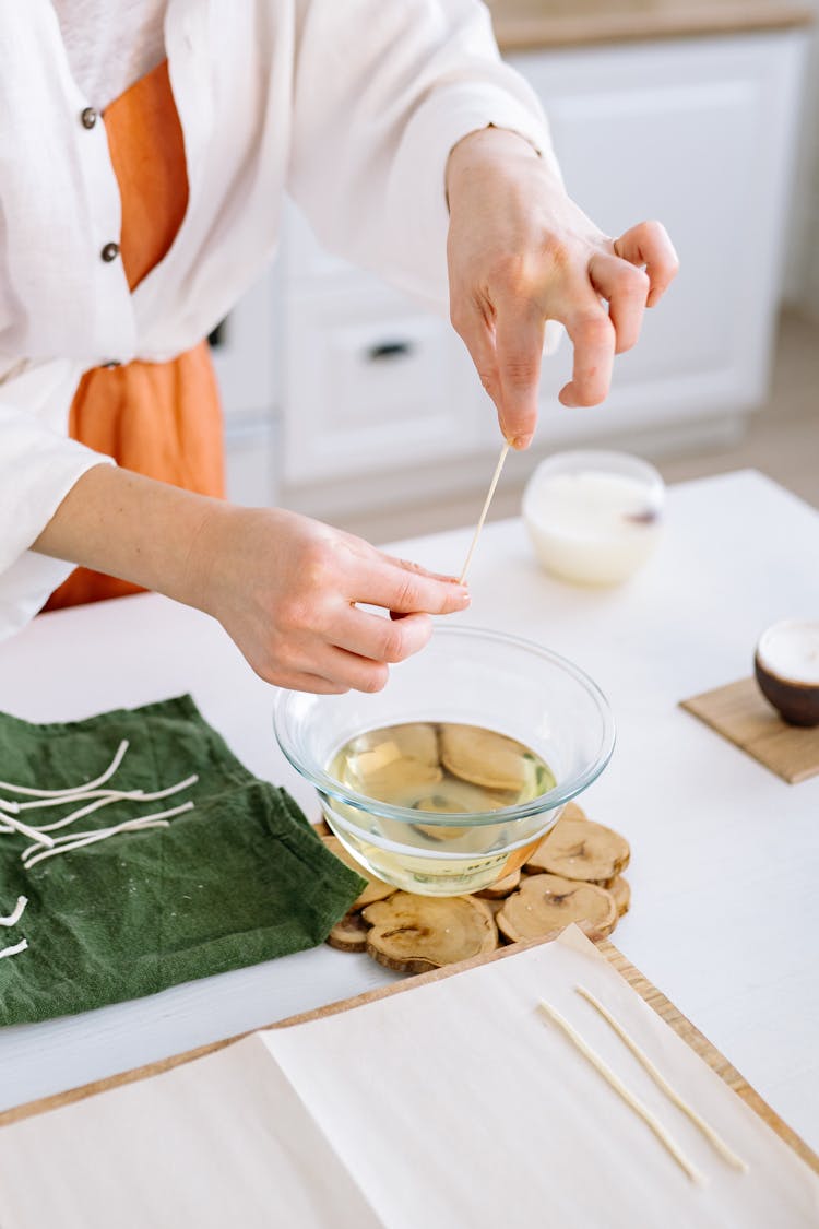 A Person Holding Candle Wick Under A Glass Bowl